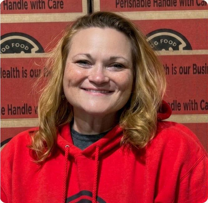 Becca smiling in a red Raw Dog Food hoodie in the warehouse