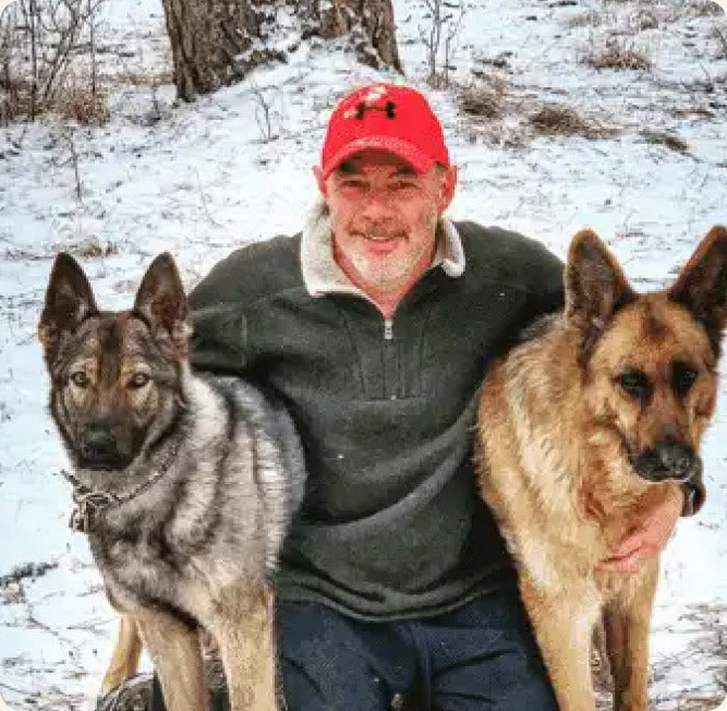Rick Moffett outdoors in the snow with his two German Shepherds