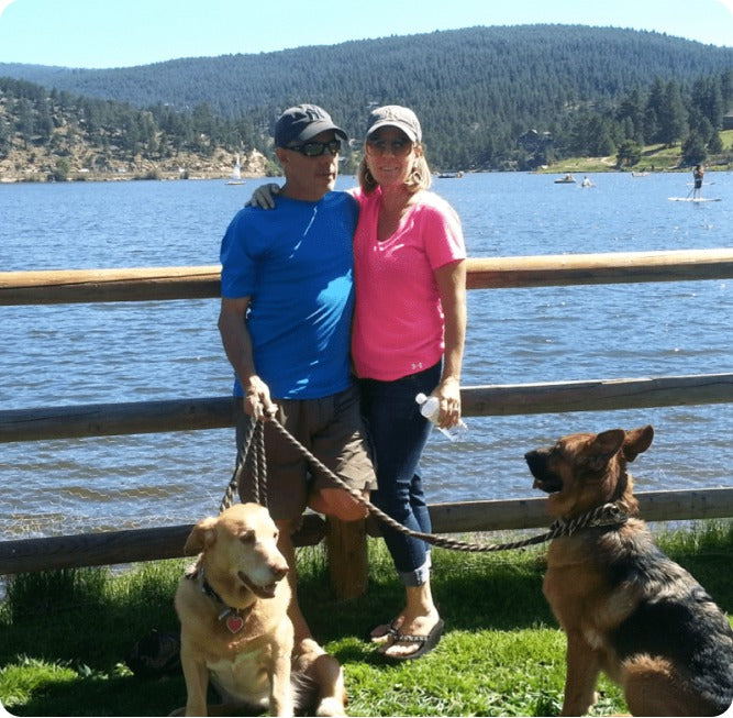 Rick and DeDe Moffett with two of their dogs beside a lake