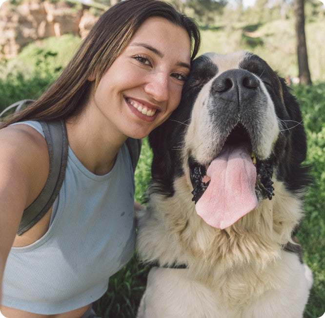 A smiling woman outdoors with her large black-and-white dog